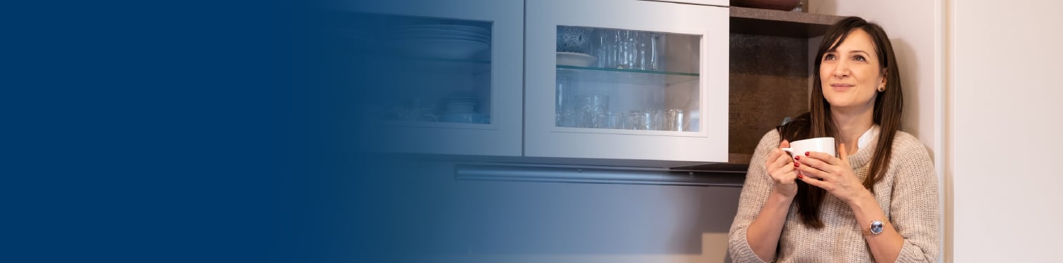 A woman in her kitchen drinking coffee